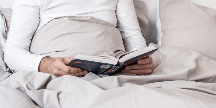 Erwachsener liest ein Buch im Bett