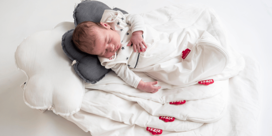 Baby sleeping on a pile of Zizzz baby sleeping bags