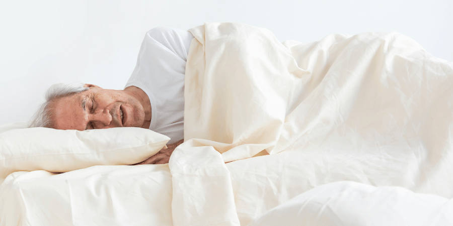 Homme âgé endormi sous sa couette