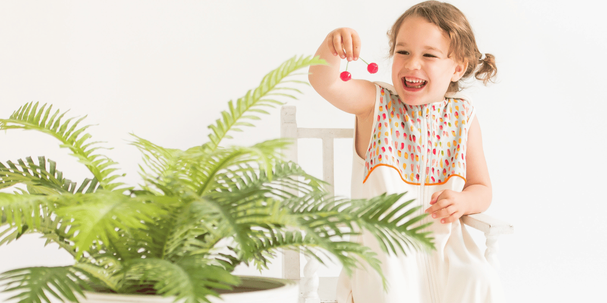 enfant qui sourit devant une plante d'intérieur 